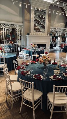 a dining room set up for an event with blue linens and red napkins