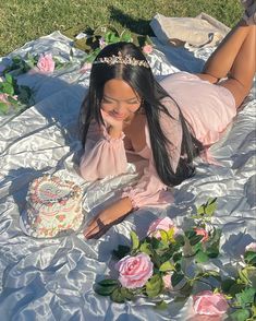 a woman laying on the ground with a cake in her hand and flowers around her