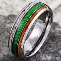 a wedding ring with green and yellow wood inlays on it's side