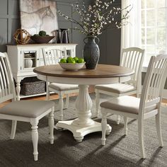 a dining room table with four chairs and a bowl of fruit on top of it