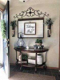 a welcome sign is hanging on the wall next to a table with potted plants