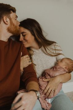 a man and woman holding a baby in their arms