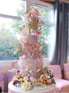 a three tiered cake decorated with flowers and fairy images on it's side