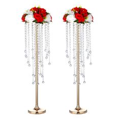 two tall metal vases with flowers and chains hanging from the sides on each side