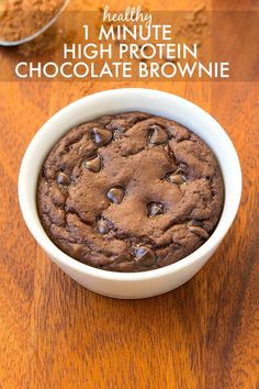 a chocolate cookie in a white bowl on a wooden table with text overlay that reads healthy 1 minute high protein chocolate brownie