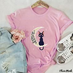 a pink shirt with a black cat sitting on the moon next to some ripped jeans