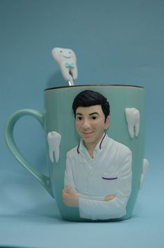 a ceramic mug with a toothbrush sticking out of it's mouth and a smiling man on the side