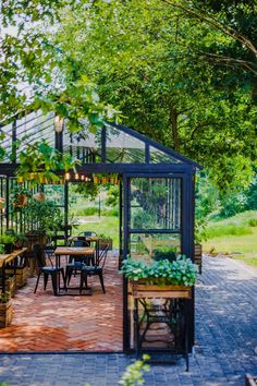 an outdoor dining area in the middle of a park with tables, chairs and potted plants