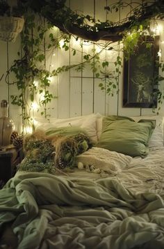 a bed with lots of pillows and blankets on top of it next to some plants