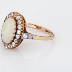 This is part of Chairish’s Fine Jewelry assortment.  Elegant antique Victorian opal & diamond ring (circa 1880s to 1900s) crafted in 9 karat yellow gold.   Natural opal measures 11mm x 7mm (estimated at 1.50 carats). 22 old mine cut diamonds total an estimated 1 carat (estimated at J-K colour and SI1-I1 clarity). The opal is in very good condition and free of cracks or crisps (some light surface abrasions from wear over the years).  The natural opal exhibits a strong colour matrix with flashes o Opal Diamond Ring, Strong Colors, Natural Opal, 1 Carat, Antique Victorian, Rose Gold Ring, 19th Century, Diamond Cuts, Diamond Ring