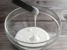 a glass bowl filled with yogurt sitting on top of a wooden table