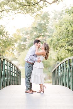 an engaged couple kissing on a bridge