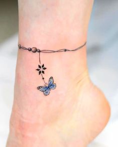 a small tattoo on the ankle of a woman's foot with a blue butterfly