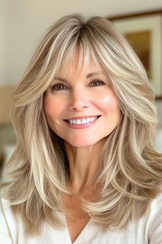 Face-Framing Feathered Layers with Long Wispy Bangs Hairstyle on a smiling woman in her 50s with blonde hair. Bangs Feathered, Light Wispy Bangs, Women Over 50 With Bangs, Over 50 With Bangs, Hairstyle With Bangs, Medium Length Hairstyle, Feathered Layers, Medium Length Hair With Bangs