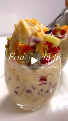 a bowl filled with fruit and cheese on top of a white table next to a spoon