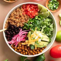 a white bowl filled with lots of different types of food next to tomatoes and avocado