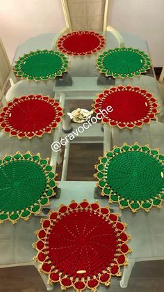 six red and green placemats sitting on top of a wooden table with white chairs