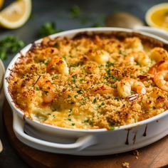 a casserole dish with shrimp and cheese in it on a wooden cutting board