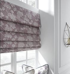 a window with roman shades and pillows on it