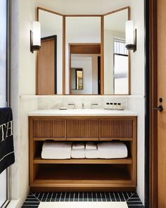 a bathroom with two sinks, mirrors and towels on the counter in front of it