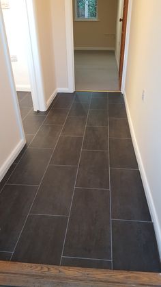 an empty hallway with tile flooring and door way leading to another room in the house