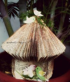 there is a small bird house made out of an old book and some flowers in it