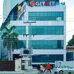 two people on a motorcycle in front of a building