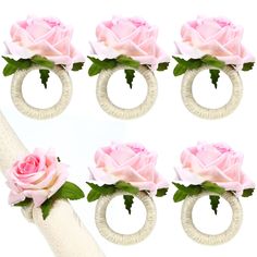 four pink roses are on top of two white rings and one is in the middle