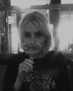 a woman holding a wine glass in front of her face and looking at the camera