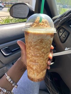 a person holding a drink in their hand while sitting in the passenger seat of a car