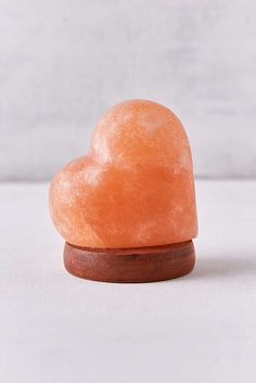 an orange heart shaped rock sitting on top of a wooden stand