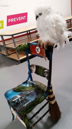 an owl sitting on top of a chair with a broom in it's mouth