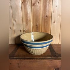 a blue and white bowl sitting on top of a wooden table next to a wall