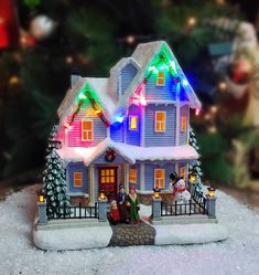 a house with christmas lights on the roof and people sitting outside in front of it