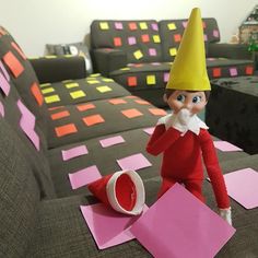 an elf is sitting on the couch with pink sticky notes in front of him and making a funny face