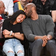 a man and woman sitting next to each other in front of a basketball game crowd