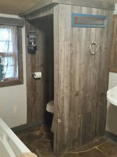 the bathroom is made out of wood and has a toilet, sink, and bathtub