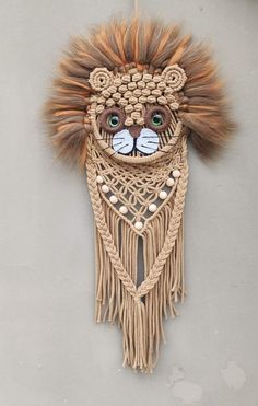 a wall hanging with a lion head on it's face and tassels