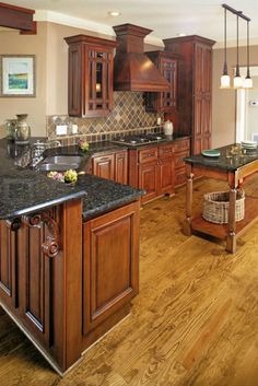 a large kitchen with wooden cabinets and black counter tops, along with an island in the middle