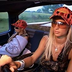 two women sitting in the back seat of a car with hats on their heads and sunglasses on