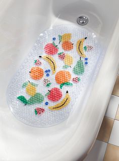 a bath mat with fruit designs on it in a white tub next to a tiled floor