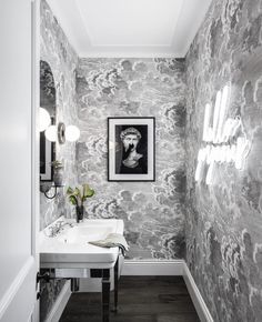 a white sink sitting under a bathroom mirror next to a wall mounted art print on the wall