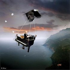 a man sitting on top of a piano with an eagle flying above him over the water