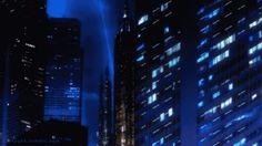 the city is lit up at night with blue lights and skyscrapers in the background