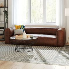 a living room with a brown leather couch and coffee table in front of a large window