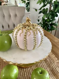 some green apples sitting on top of a white plate with gold beading around them