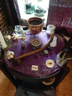 a table topped with candles and other items on top of a purple cloth covered table