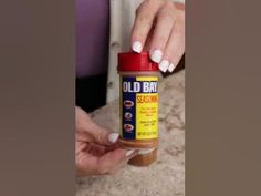 a woman holding a bottle of old bay seasoning on top of a countertop