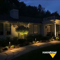 a house that is lit up at night with lights on the front and side of it