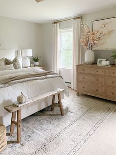 a bed room with a neatly made bed and a wooden bench in front of a window